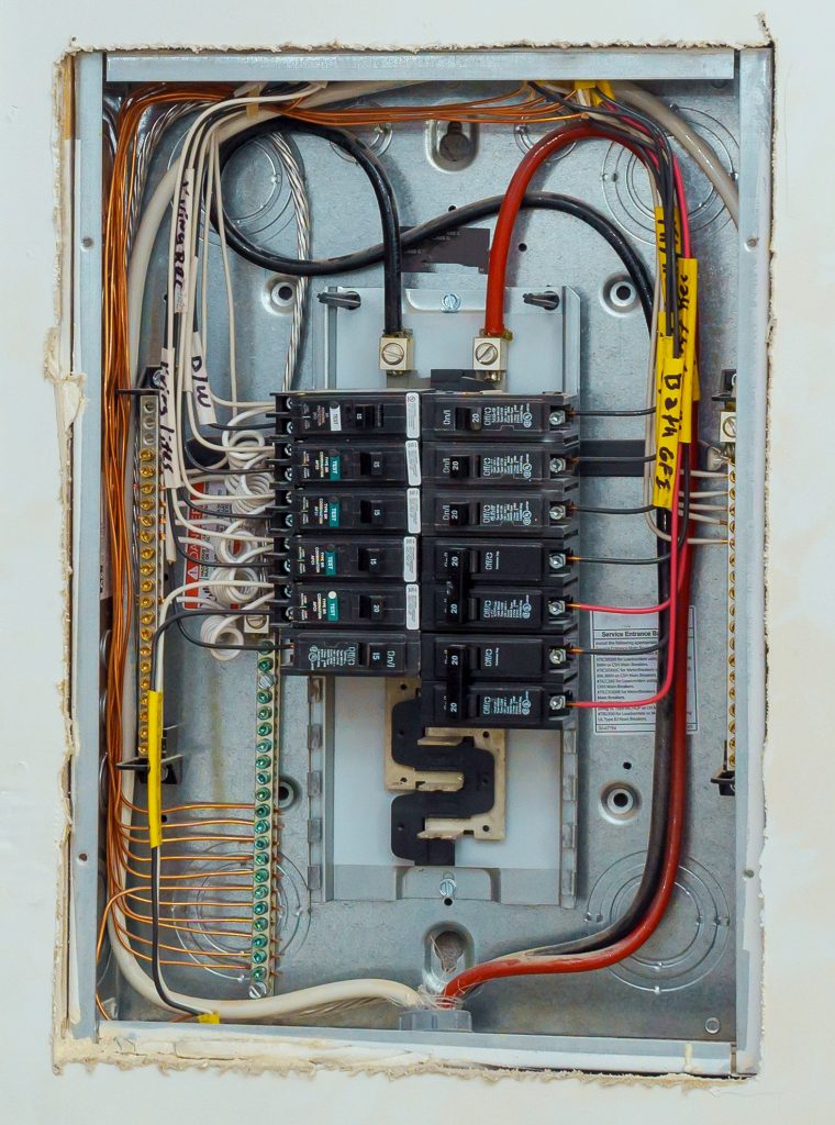 Electrical voltage switchboard box with wires with circuit breakers.