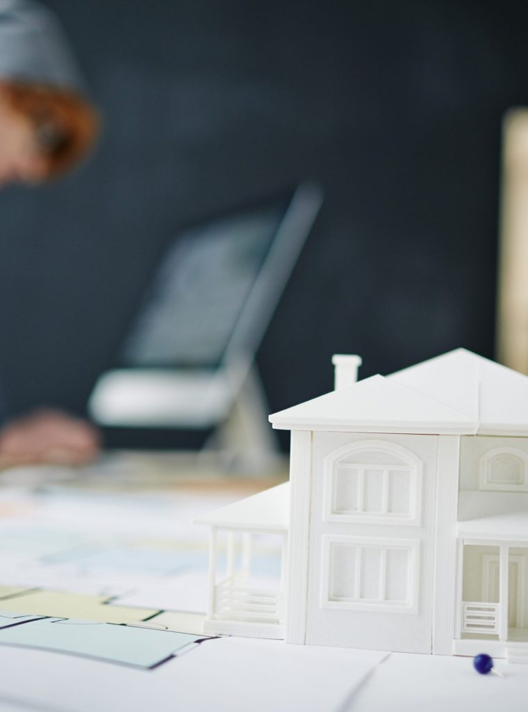 Model of house on table with man working in the background