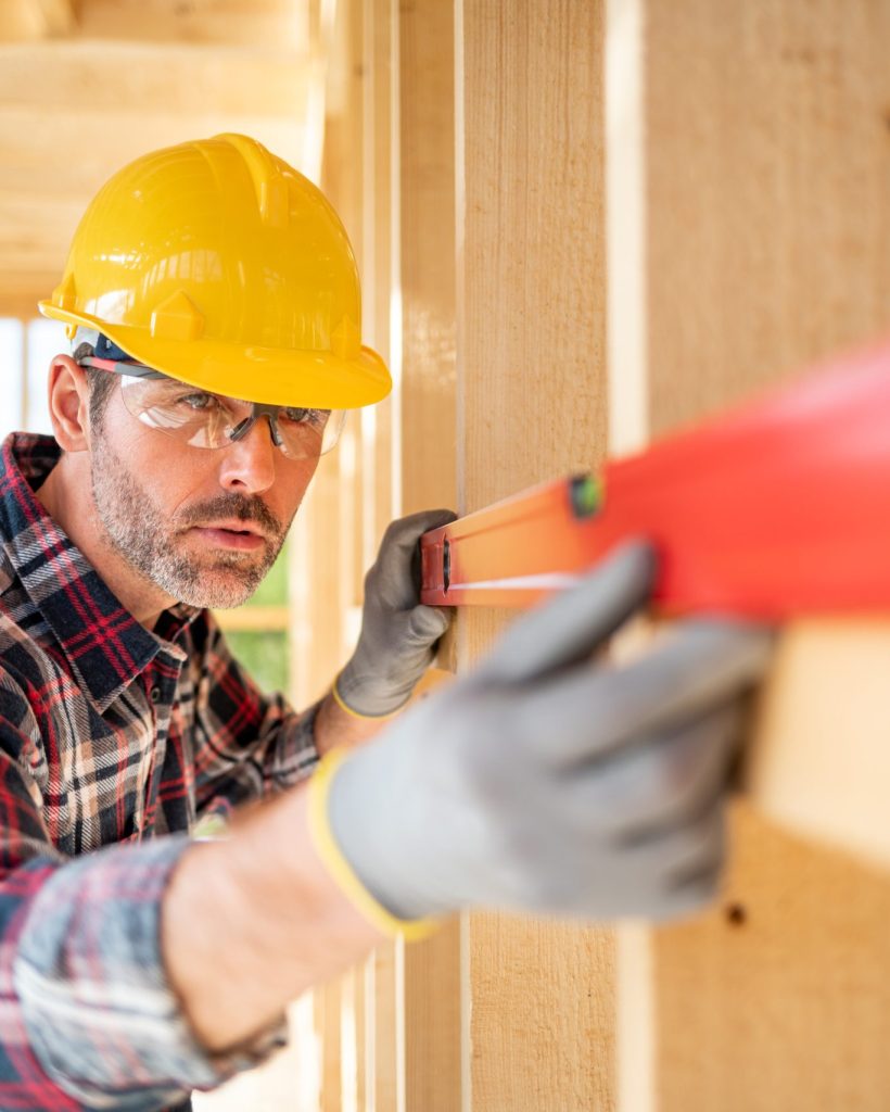 Worker using level tool measure frame house construction